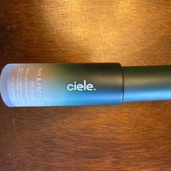 SEPHORA - The winner - A cylindrical bottle of Cielé tinted moisturizer with SPF 50 is placed on a wooden surface, showing the product label and branding. - Cosmetics & Beauty Supply Near Me - Pasadena, California