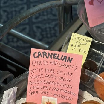 Crystal Dragon - Carnelian - Carnelian stones are shown with handwritten notes describing their qualities and price, displayed on a cart or table. - Jewelry Near Me - Boulder, Colorado