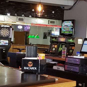 In Plane View - a bar and televisions - A bar with multiple screens, gaming machines, and a dartboard, with a menu board and condiments visible. - American Near Me - Milwaukee, Wisconsin