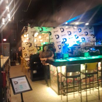 Disco Chicken - A woman is positioned behind a bar counter in a nightclub or bar with colorful lighting and patterned wallpaper. - Chicken Shop Near Me - Rockford, Illinois
