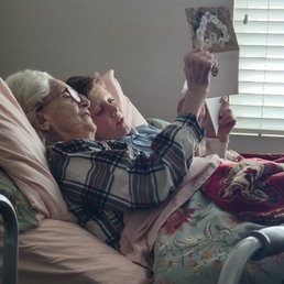 Omi enjoying her new bed with her grandson, looking over pictures from back home. Omi enjoying her new bed with her grandson, looking over pictures from back home.
