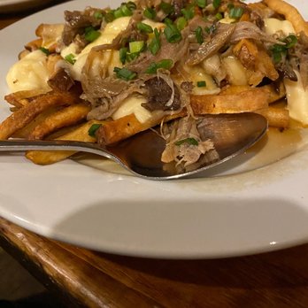Johnny Seesaw's - Poutine was excellent! Cheesy with a rich gravy and tasty fries! - A serving of poutine with fries, cheese curds, gravy, shredded meat, and chopped green onions on top. - American Near Me - Peru, Vermont