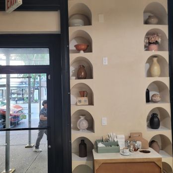 Stop By Café - Facing the entrance and design of assorted pottery on the wall - Bakeries Near Me - New York, New York Stop By Café - Facing the entrance and design of assorted pottery on the wall - Bakeries Near Me - New York, New York
