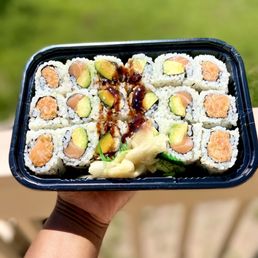 a hand holding a tray of sushi a hand holding a tray of sushi