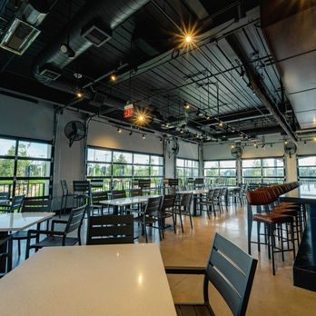 PopStroke - Indoor dining area with garage-style doors that open up, with the option to keep them closed. - Mini Golf Near Me - Cedar Park, Texas PopStroke - Indoor dining area with garage-style doors that open up, with the option to keep them closed. - Mini Golf Near Me - Cedar Park, Texas