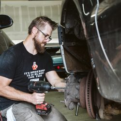 Fort Collins Complete Auto Repair - Mechanic working on wheels of car.