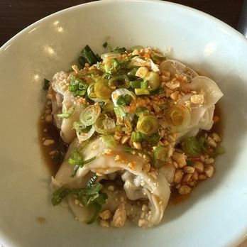 Dumpling Wei - Wontons - A white bowl holds several dumplings topped with chopped green onions and crushed peanuts. The dumplings are served with a soy-based sauce visible at the bottom of the bowl. The presentation emphasizes the garnishes and the sauce, typical of Asian cuisine. - Chinese Near Me - Pasadena, California