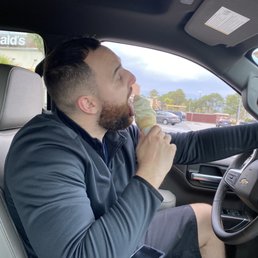 a man eating a hot dog in a car