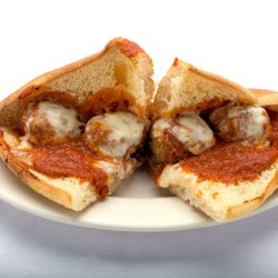 Genova’s To Go - A delicious meatball sub from Genova's To Go - a plate with a sandwich filled with meatballs and cheese.