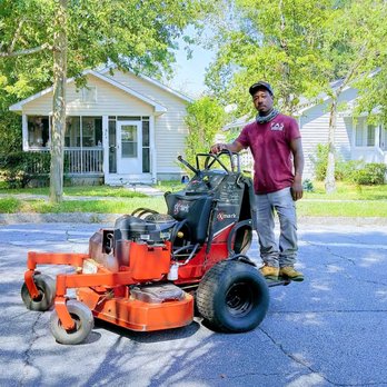 Fas Lawncare - a man standing next to a lawn mower - Lawn Services Near Me Fas Lawncare - a man standing next to a lawn mower - Lawn Services Near Me