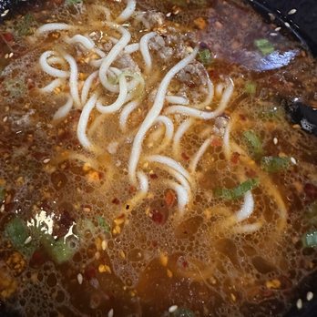 Fun Noodle Bar - 32. Tonkotsu Spicy Ramen - Spicy ramen with noodles, green onions, and chili flakes in a broth, served in a black bowl. - Chinese Near Me - Santa Fe, New Mexico