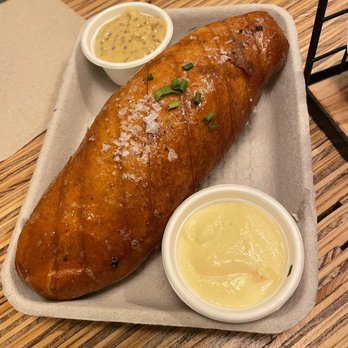 Forward Brewing - Pretzel and dip - A baked sweet potato garnished with chopped green onions, accompanied by two dipping sauces, on a rectangular tray at a restaurant. - Brewpubs Near Me - Annapolis, Maryland