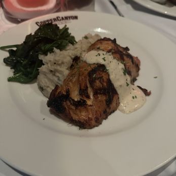 Copper Canyon Grill- Silver Spring - Salmon - A dinner plate featuring grilled chicken with a creamy sauce, mashed potatoes, and sautéed greens at Copper Canyon Grill in Silver Spring, MD. - American Near Me - Silver Spring, Maryland