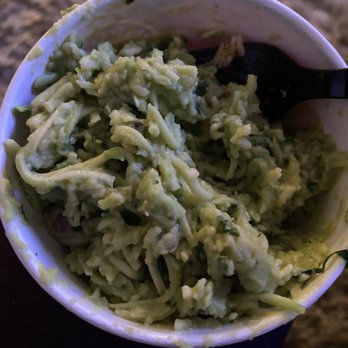 Chipotle Mexican Grill - Cheese all in the guac - A bowl of guacamole with chunky avocado pieces and herbs, served with a black spoon. - Mexican Near Me - Hanover, Maryland