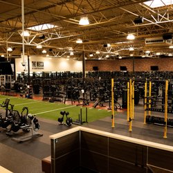 Gold's Gym - Wide view of the fitness floor at our Greeley gym featuring rows of stationary bikes, a green functional training turf area, ...