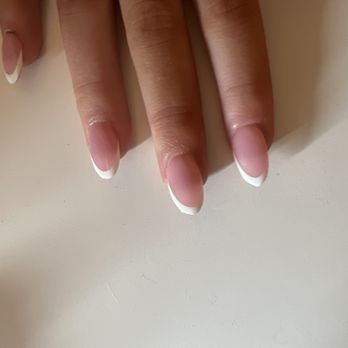 JL Nails - What a shame don't go get better!!! - A hand with neatly manicured nails featuring a French manicure rests on a plain, light-colored surface. - Nail Salons Near Me - Howell, Michigan