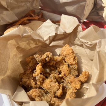 Herban Vegans - Oyster mushroom wings - Crispy fried oyster mushroom wings placed in a paper-lined basket, with additional food items and paper bags visible in the background. - Vegan Near Me - Cincinnati, Ohio