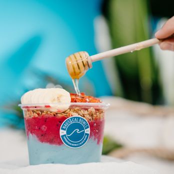 Nautical Bowls - a hand holding a spoon and scooping some fruit into a cup - Acai Bowls Near Me - Estero, Florida