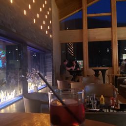 Fireside - Interior of a bar or restaurant with wooden beams, large windows, and decorative lighting, showing patrons seated at tables.