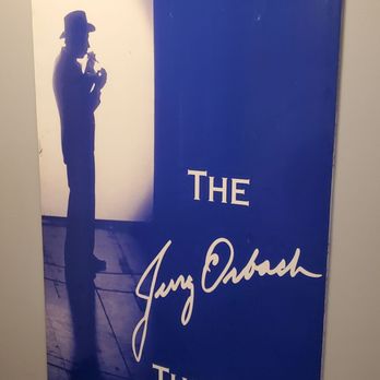 Jerry Orbach Theater - a man standing in front of a blue sign - Performing Arts Near Me - New York, New York