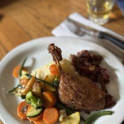 Duck confit served with apple chutney, mashed potatoes and roasted vegetables.
