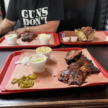 Racks BBQ - a man sitting at a table with two trays of food - Barbeque Near Me - Pittsburg, Texas