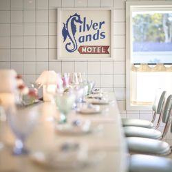 Nookies - A stylish nod to retro diner culture at Nookies, featuring a long, classic counter with mint-green stools and a vintage Silver Sands sign.