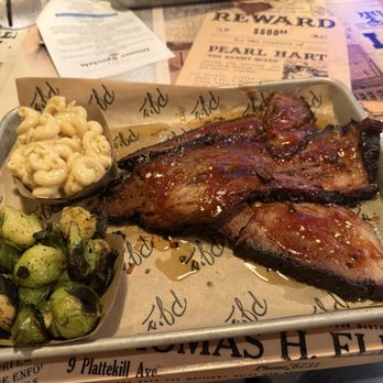 PJ's Smoke & Grill - Brisket, Mac and Cheese and Brussels sprouts - A metal tray holds barbecue ribs glazed with sauce, alongside macaroni and cheese and roasted Brussels sprouts, on a restaurant table. - Barbeque Near Me - Medway, Massachusetts