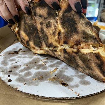 Falco's Pizza - a person holding a piece of pizza - Pizza Near Me - Cicero, Illinois