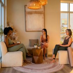 Goji Yoga & Wellness - Three women chatting in the lounge space at Goji Yoga & Wellness in Oakville.