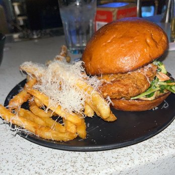 Rooted Craft Kitchen - Nashville hot chicken sandwich - A Nashville hot chicken sandwich with a brioche bun, fried chicken, lettuce, and sauce, served with fries topped with shredded cheese. - New American Near Me - Boulder, Colorado