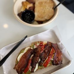Noontide Coffee Kitchen - Anything + Everything Avocado toast with peppercorn bacon and in the back, Scram-Bowl with grits, bacon, toast!