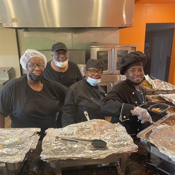 Wammy’s Kitchen - The talented artists at work - Four staff members in chef uniforms and hair coverings stand behind a counter with food trays at Wammy’s Kitchen, Rockford, IL. - Burgers Near Me - Rockford, Illinois