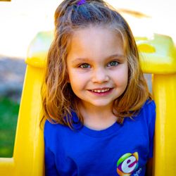 Mt. Elizabeth Academy - A little girl in a blue shirt sitting on a yellow slide.