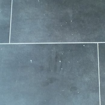 Floored - The white specks are chips...they were also covered by a piece of cardboard when the transition was being installed. - Flooring Near Me - Austin, Texas