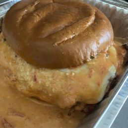 Drunken Chicken Parm sandwich - The image features a chicken pot pie with a golden-brown biscuit topping, placed in a rectangular metal baking dish. The filling appears creamy with visible chunks of chicken and vegetables, and melted cheese is seen around the edges of the dish. The biscuit topping is smooth and slightly shiny, indicating it has been baked to a golden finish.