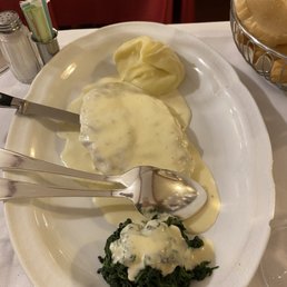 Veal covered in cheese and sauce with spinach and mashed potatoes.