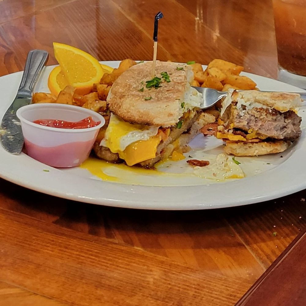Rustic Table - Snuck a picture of my neighbors sausage breakfast sandwich. As big as a hamburger! - Southern Near Me - Pawleys Island, South Carolina Rustic Table - Snuck a picture of my neighbors sausage breakfast sandwich. As big as a hamburger! - Southern Near Me - Pawleys Island, South Carolina