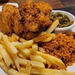 Fried pork chop, dirty rice, green beens, and French fries.