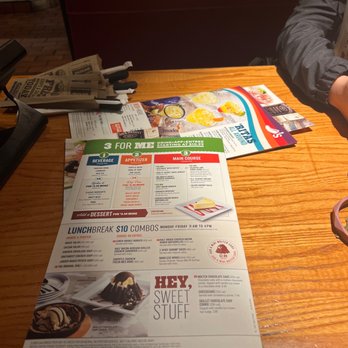 Chili's - A restaurant menu is placed on a wooden table, with a person partially visible on the right side. The menu features food and drink options, including desserts. - Bars Near Me - Albuquerque, New Mexico