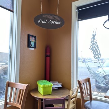 Great Harvest Bread - Kids corner - A corner labeled 'Kids' Corner' features a small round table with chairs, a sign hanging from the ceiling, and a window with decorative decals. - Coffee & Tea Near Me - Cedar Rapids, Iowa