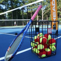 Tennisbloc - Tennis racquet and tennis balls on a tennis court.