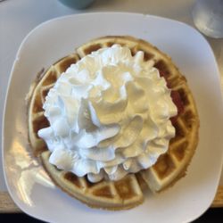 Boudreau's Bistro & Bakery - Two waffles with strawberries and whipped cream. Hot chocolate with whipped cream to drink!