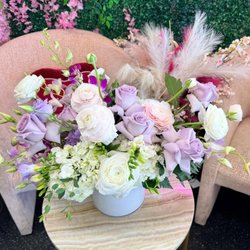 An elegant arrangement of lavender roses, white hydrangeas, ranunculus, and delicate accent blooms in a modern white vase.