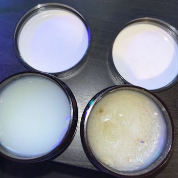 Target - Moldy pomade - Four small, round, open containers of creams or ointments are arranged on a dark surface. The contents vary in appearance: two are white, one is a slightly yellowish or pale greenish cream, and another appears to have a yellowish, slightly textured surface with some bubbles or foam. The containers are made of clear or dark plastic, and the image is taken from above, showing the different consistencies and colors of the products. - Department Stores Near Me - Milltown, New Jersey