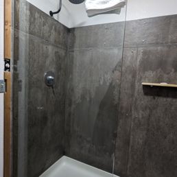Shower stall with what looks like bare concrete walls (it's not, but it looks like it) Shower stall with what looks like bare concrete walls (it's not, but it looks like it)