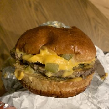 Hamburger Stan - a hand holding a hamburger with cheese and pickles - Food Delivery Services Near Me - Chicago, Illinois Hamburger Stan - a hand holding a hamburger with cheese and pickles - Food Delivery Services Near Me - Chicago, Illinois