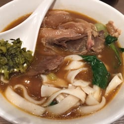 小王牛肉麵 - Beef and tendon with thick noodles in soup. Garnished with pickled vegetables.