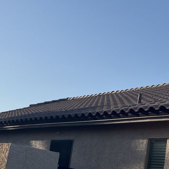 Monsoon Roofing - A house roof with dark-colored tiles and a small vent, set against a clear blue sky. - Roofing Near Me - Gilbert, Arizona
