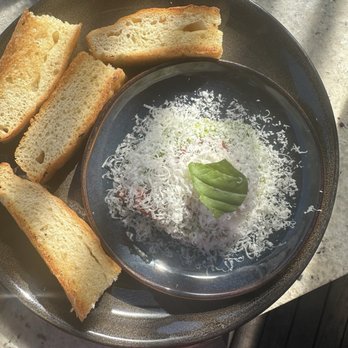 Nido - Avocado toast - Toasted bread slices are arranged on a plate next to a bowl of shredded cheese garnished with a basil leaf. - New American Near Me - Austin, Texas